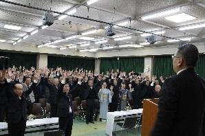 中央公民館に集まった参加者が一同に両手を上に挙げて、万歳三唱をしている写真
