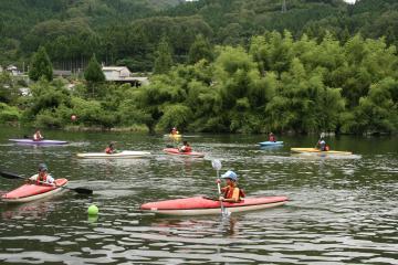参加者の乗ったカヌーが由良川に8艘出ており、パドルを両手で持って漕ぎながらカヌー体験を楽しんでいる写真