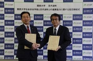 関西大学社会安全学部の安部誠治学部長と太田昇町長が握手している写真