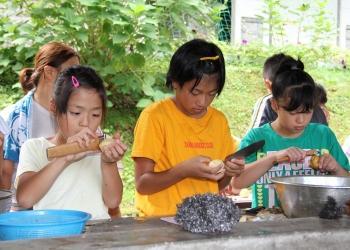 3人の女の子達が横に並んで、真剣な表情でジャガイモの皮むきをしている写真