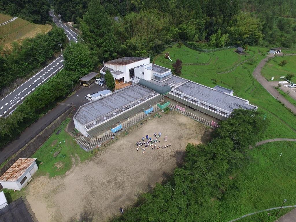 令和2年7月20日の工事着手前、南東から撮影した写真。旧園舎と運動場に集まった園児と先生の航空写真。