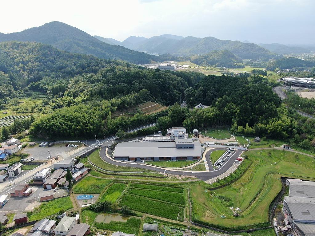 令和3年7月29日の工事進捗、東から撮影した写真。駐車場に車が停まっており、新しい園舎の前に旧園舎が見える状況の写真。