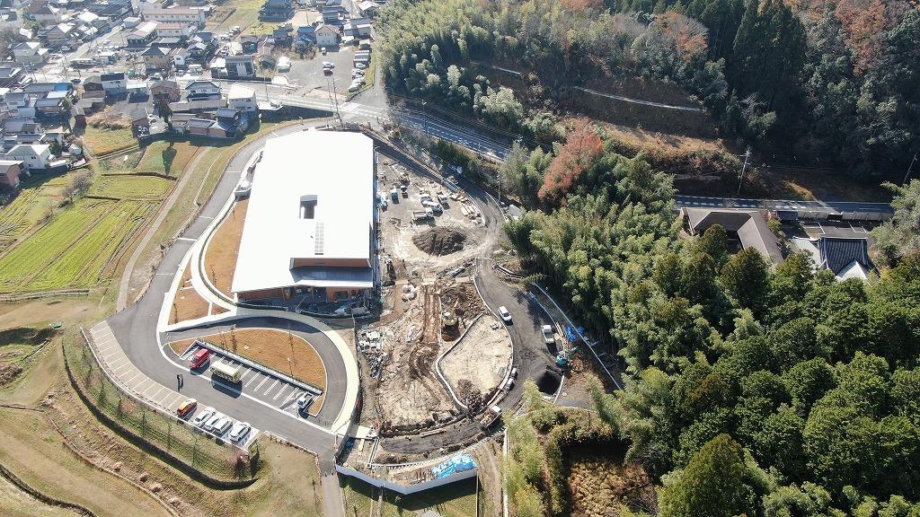 令和3年12月3日の工事進捗、北から撮影した写真。建物の屋根が白くなっており、園舎前の土地に工事車両が沢山入り作業が行われている状況の写真。