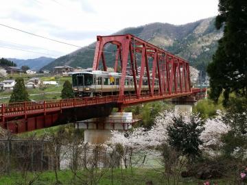 由良川の上の赤い鉄道橋を通過する電車の写真