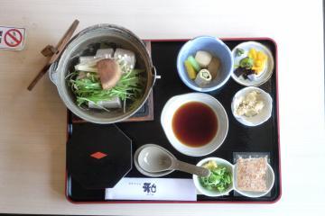 四角のお盆の上に湯豆腐定食の湯豆腐や薬味などが並んでいる写真