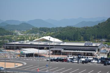 手前に駐車場、奥に白の横長の建物が建っている道の駅「京丹波味夢の里」の外観写真