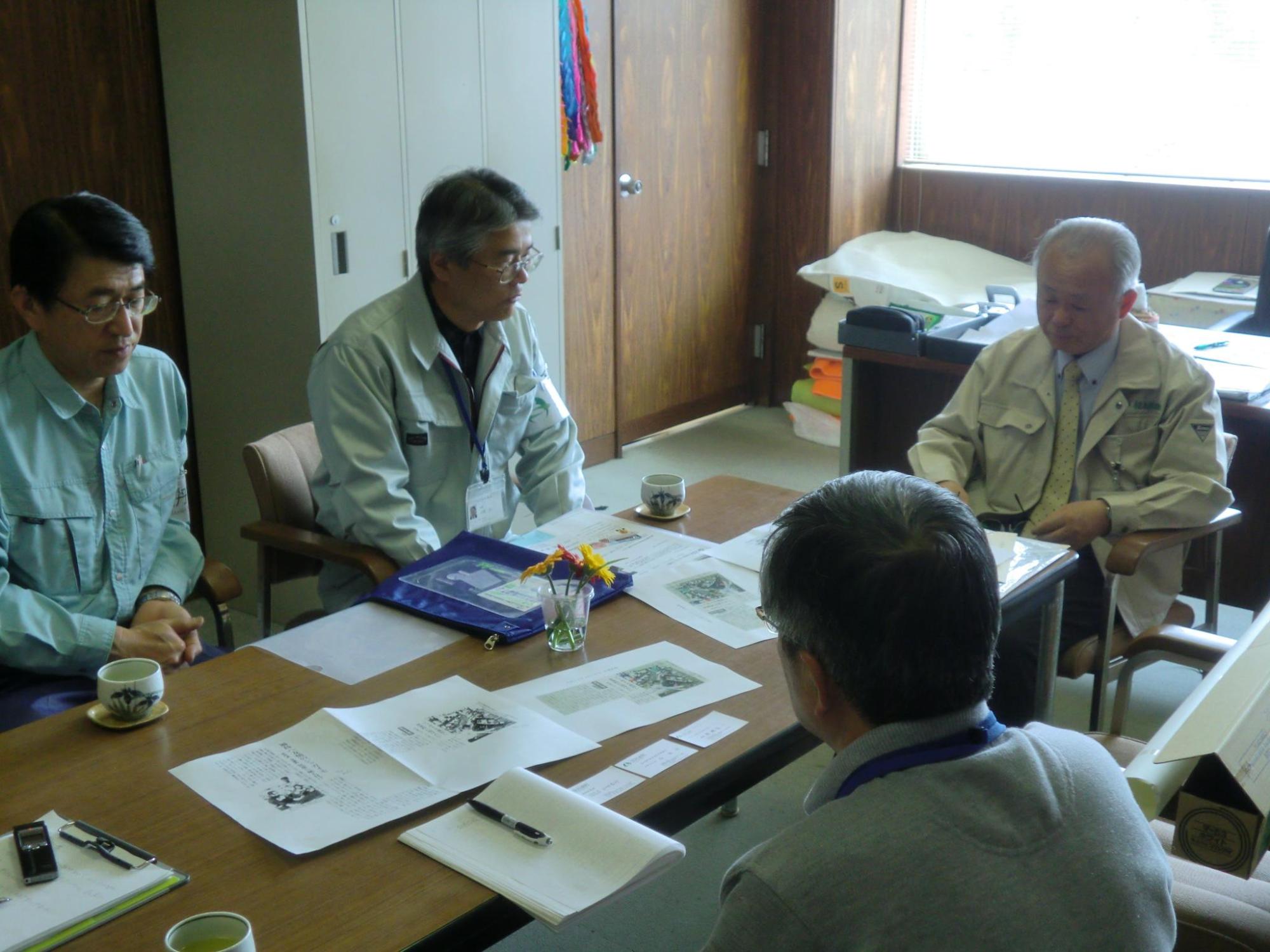 井戸川町長と調査団の3名が資料が置かれた机を囲んで座り、話をしている写真