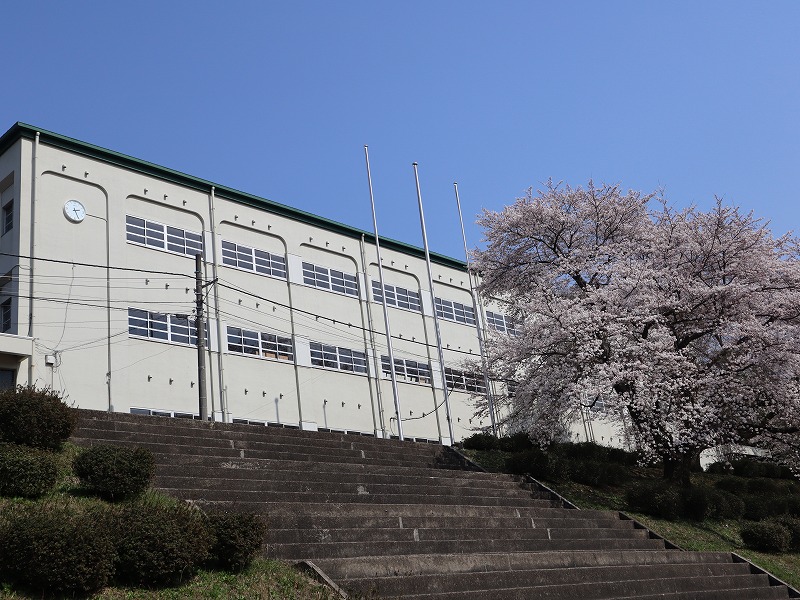 白い外壁の3階建ての校舎で正面玄関から奥まで校舎が続いている和知中学校の外観写真