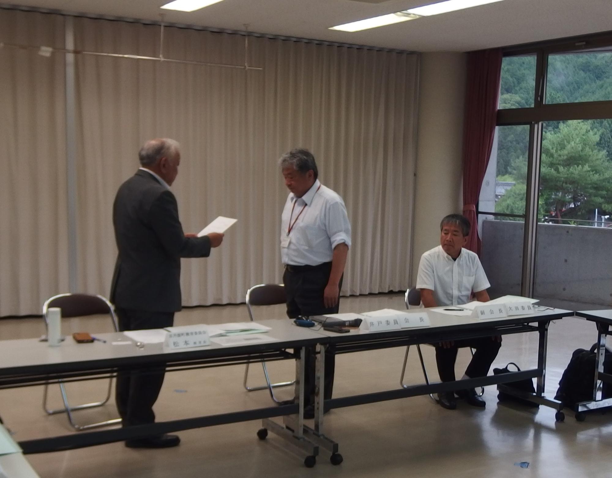 井戸会長に諮問書を手渡す松本教育長