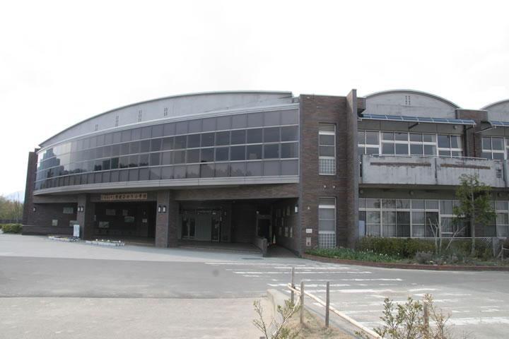 コンクリート調の建物で、2階部分が丸みがかっており、一面が縦4枚の四角の窓になっている丹波ひかり小学校の外観写真
