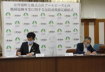 議場にて地域協働事業に関する包括連携協定にサインをする太田町長と天羽専務取締役の写真
