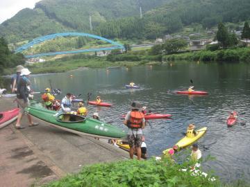 川岸から由良川へカヌーを降ろしている参加者や川の中をカヌーに乗って進んでいく参加者の写真