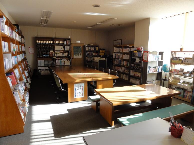 壁際に本の並んだ本棚が設置され、室内の中央に机と椅子が設置されている山村開発センターみずほ図書室内の写真