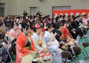 艶やかな振袖を着た新成人が会場に設置されたパイプ椅子に座っている成人式の会場内の写真