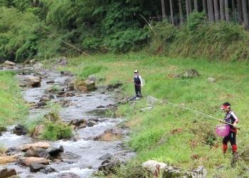 上和知川の岩がゴロゴロとした川幅の狭い場所で、竿を下ろし魚釣りをしている人が2名写っている写真