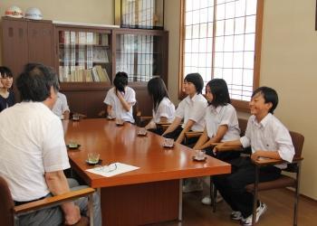 中学生6人と町長が向かい合って座っており、笑いながら楽しそうに談笑している写真