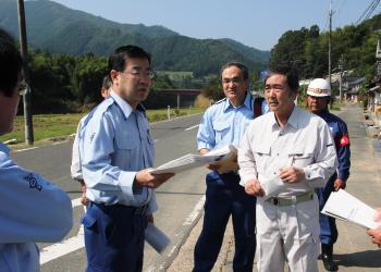 資料を手に持ち、現場の状況を見ながら話しをしている山田啓二知事と関係者の写真
