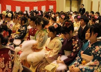 艶やかな振袖を着た多くの新成人の皆さんが会場内の席に座っている成人式の様子の写真