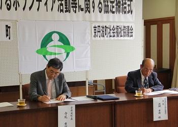 寺尾町長と町社会福祉協議会の波瀬孝澄会長が並んで長机に座っており、協定書に調印している写真