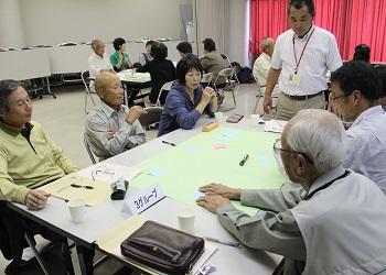 参加者の皆さんが6名のグループに分かれて席についており、真剣な表情で話し合いが行われている写真