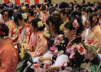 艶やかな振袖を着た沢山の新成人が成人式会場の椅子に座っている写真