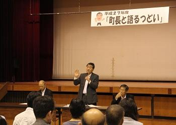 舞台上に「町長と語るつどい」と書かれた横断幕、町長が参加者の前でマイクを持って話をしている写真