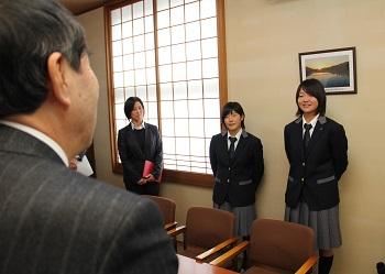 制服姿の平田さんと的場さんが町長と向かい合って立ち、決意を述べている写真