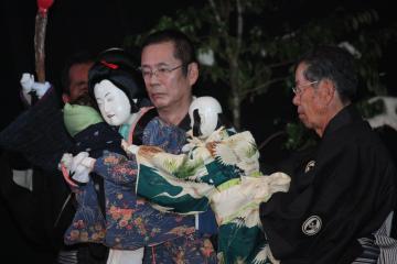 紋付き袴を着た男性2名が着物を着た女性と子どもの人形をそれぞれ操って演じている和知人形浄瑠璃会による舞台の様子の写真