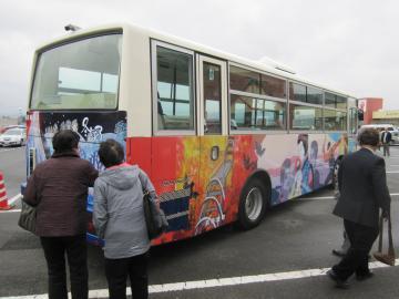 赤や黄色の色がメインに使われている質志鐘乳洞公園や車体中央に描かれた和知人形浄瑠璃の車体右側のラッピングバスの写真