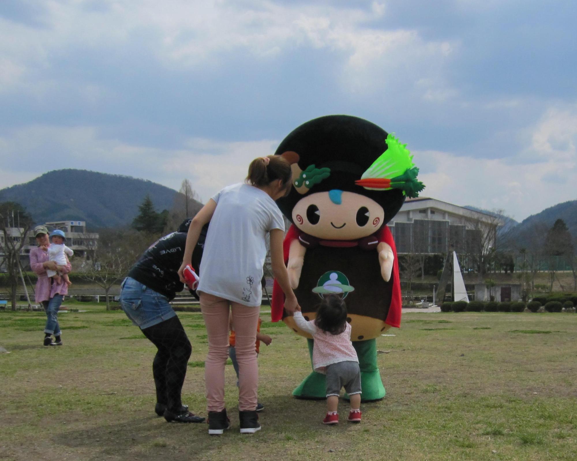 お母さんに手を引かれながら味夢くんに寄っていく小さな子供に味夢くんが両手を差し伸べている写真