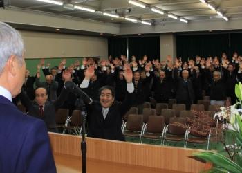公民館に集まった多くの参加者の皆さんが両手を上に挙げて、万歳三唱をしている写真