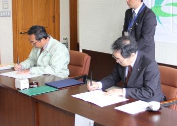 寺尾豊爾町長と建設業協会の野口芳彦会長が横に並んで座っており、協定書に調印している様子の写真