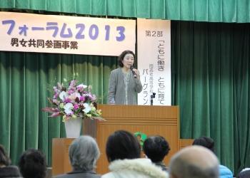 綺麗な檀上の花の横の講演台に立ってマイクを持って話をしている講師のバーグランド薫さんの写真