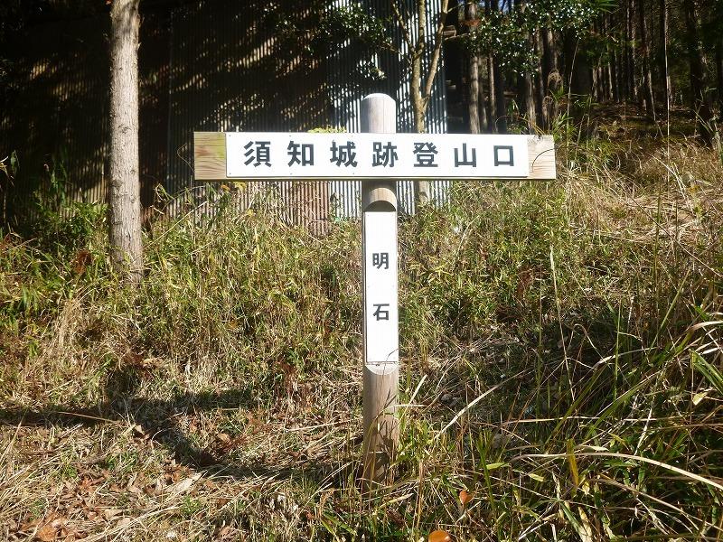 須知城跡登山口を指し示す看板が草むらの中に立っている写真