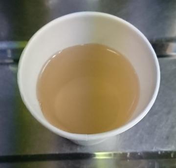 煮出しした薄茶色のヤブニッケイ茶を紙コップに入れている写真