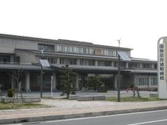 「国保京丹波町病院」と書かれた看板と植木、横に長い造りになっている3階建ての京丹波町病院の写真