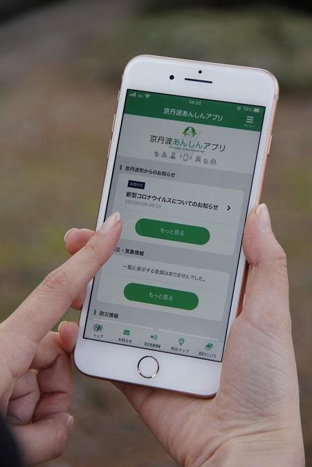 京丹波あんしんアプリの画面が表示されたスマートフォンを操作しようとしている写真
