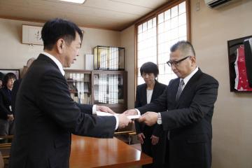 湊会長が太田町長へ答申書を手渡しし、出野副会長が後方より見守っている写真